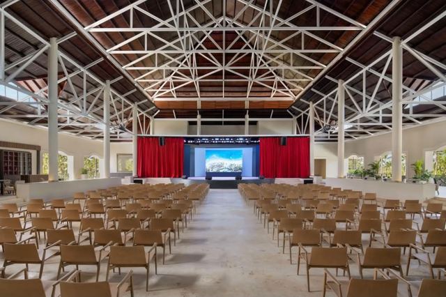 Theatre and event hall with rows of chairs facing a stage and screen