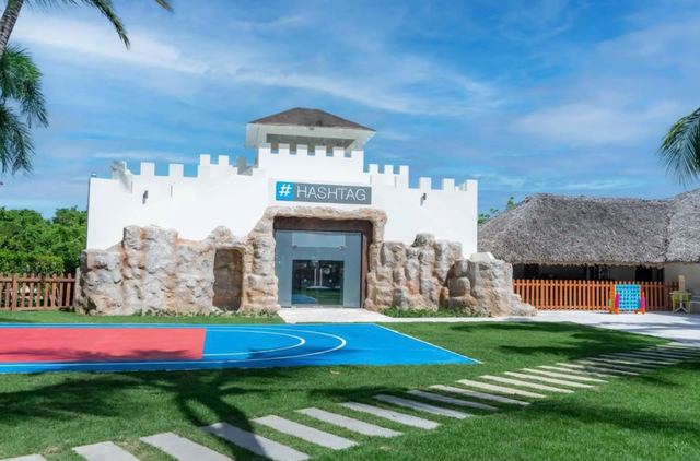 Castle-style kids club building beside a painted sports court