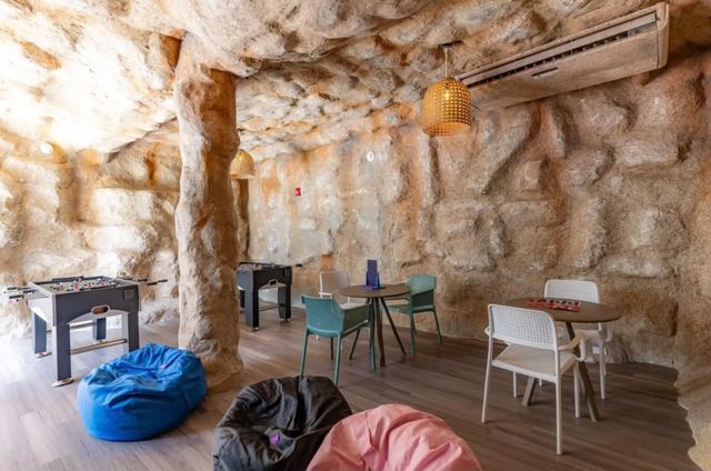 Cave-themed games room with rock walls, beanbags and tables