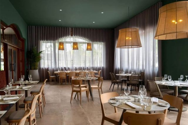 Restaurant dining room with set tables under large woven pendant lights