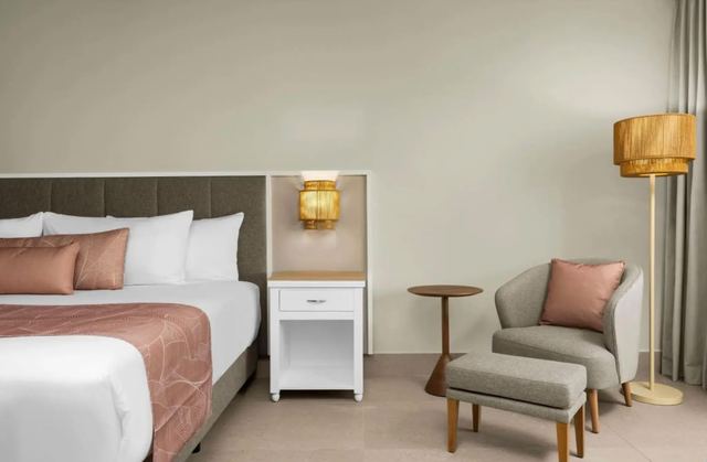 Guest room with a lounge chair, footstool and floor lamp beside the bed