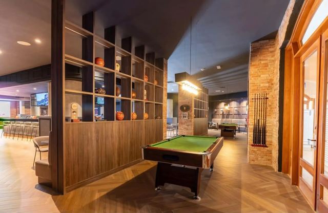 Lounge with a billiards table, wood shelving and stone walls